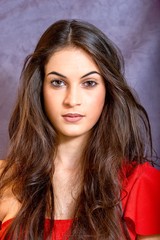 black hair woman portrait with brown eyes  on a gray background , Caucasian ethnic group is looking into the camera with a serious expression on her face. White girl with long black hair and brown eye