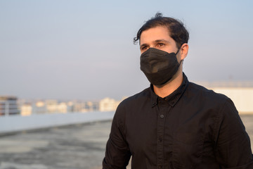 Young Persian businessman thinking while wearing mask for protection from corona virus outbreak and pollution