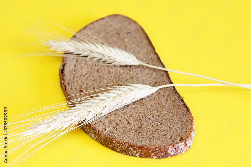 Wall mural a piece of black bread and a ear of rye placed on an bile background