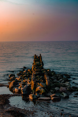 view of the sea or ocean at sunrise or sunset in quiet weather with sea stones and sand