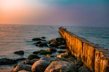 view of the sea or ocean at sunrise or sunset in quiet weather with sea stones and sand