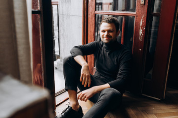 Happy guy sitting in the room. Happy man sitting on the floor.