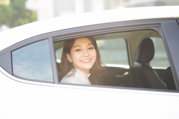 Beautiful woman smiling while sitting on back seat in the car. The lady is looking through the window.