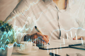 Fototapeta premium Double exposure of man's hands writing notes of stock market with forex chart.