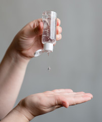 Close up hands of woman useing antibacterial sanitizer on gray black background.