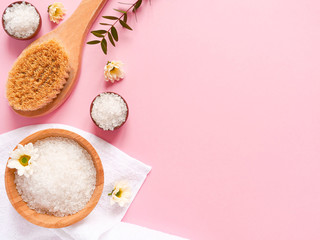 Spa flatlay composition. Sea salt, bath towel, massage wooden brush, flower, plant on pink background. Copyspace, top view. Home care concept, relax and rest