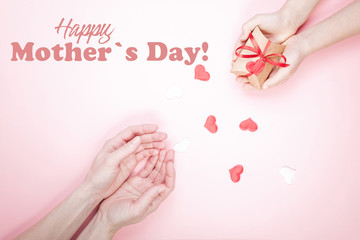 Mother's day greeting card on a pink background. Children's hands and female hands. Gift box and hearts.