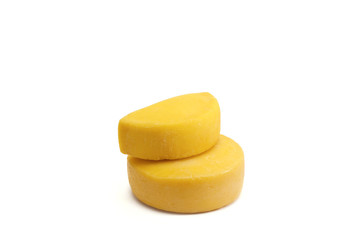 Two classic cheese heads, one of which is cut in half on a white background.