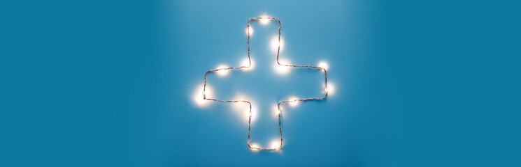 Croce sanitaria con mascherina chirurgica su sfondo bianco. Concetto di soccorso per Coronavirus covid-19. Banner. Panoramica.