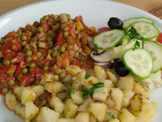 Kartoffelsalat mit sautierten Erbsen und Tomaten sowie frischer roher Gurke und Champignon