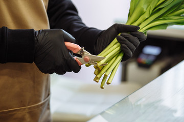 florist girl trims the tips of white tulips in a flower shop
