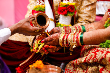 Fototapeta premium Traditional indian wedding ceremony, groom holding hand in bride hand