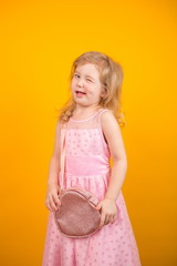 Little girl in a pink dress standing on a yellow background