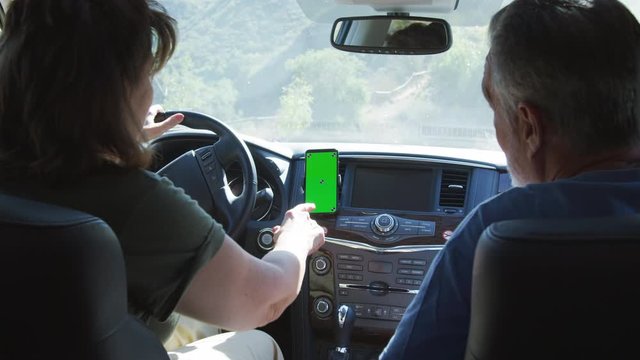 Rear View Of Senior Hispanic Couple On Drive Through Countryside Using Sat Nav On Mobile Phone - Shot In Slow Motion