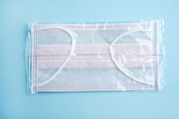 Disposable pink disposable medical mask on light blue background