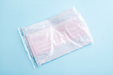 Disposable pink disposable medical mask on light blue background