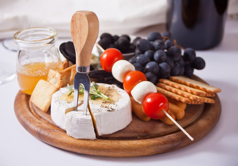 plate with assorted cheese, fruit and other snacks for party.