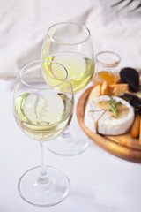 Two glasses of white wine and plate with assorted cheese, fruit and other snacks for party