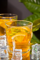 Two glasses of cold refreshment tea with ice and lemon fruit.
