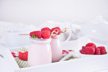 Two portions natural homemade yogurt in a glass jar with fresh raspberry. Breakfast concept.