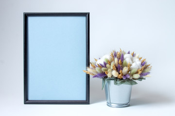 black photo frame and decorative arrangement of dried flowers on a white background with copy space