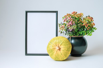 black photo frame, bright autumn pumpkin and decorative vase with flowers on a white background with copy space