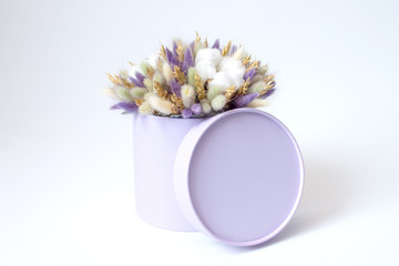 composition of dried flowers in a lilac hat box on a white background