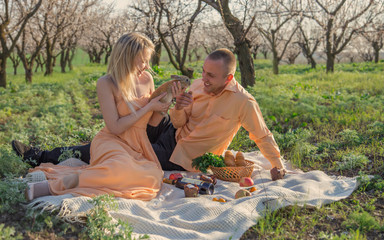young guy and girl had a picnic in nature. girl holds a rabbit in his hands and shows it to a young man