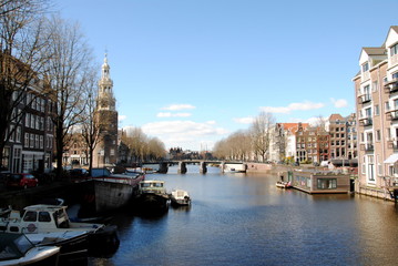 Obraz premium View on the Montelbaanstoren, a tower on the bank of the Oudeschans canal in the citycenter, built in 1516 as part of the Walls of Amsterdam defending the city and the harbour; National Monument