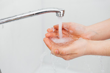 Girl washes her hands under water with soap. Hand disinfection