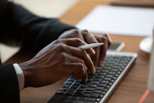 Typing text, close up. African-american entrepreneur, businessman working concentrated in office. Looks serios and busy, wearing classic suit. Concept of work, finance, business, success, leadership.