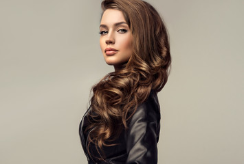 Beautiful stylish woman wearing  black leather jacket. Fashionable and self-confident girl with long curly hair. Clothing, style and fashion - obrazy, fototapety, plakaty
