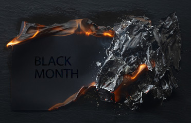 Burning piece of black paper with the word 