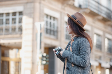 Beautiful brunette tourist girl holding a camera in her hands.