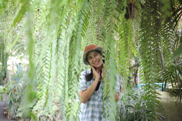 Smiling woman and nephrolepis sp fern leaves in a garden, Thailand