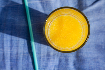 A glass of fresh citrus juice on a blue background. The view from the top, drink in the sunlight.