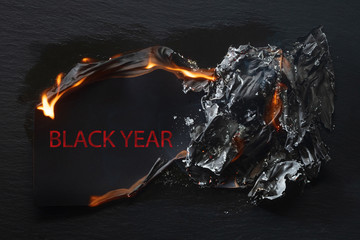 Burning piece of black paper with the word 