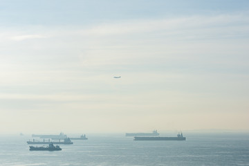 Fototapeta na wymiar Cargo ships and oil tankers anchored offshore along the Singapore Straight, in Singapore
