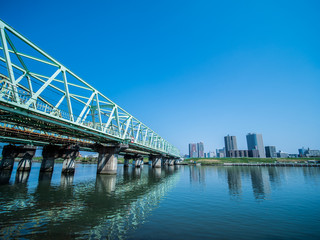 青空の東京北区赤羽の荒川を渡る鉄橋と対岸の川口市の風景