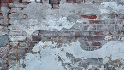 Old red brick wall background partially exposed under multiple layers of crumbling concrete. Copy...
