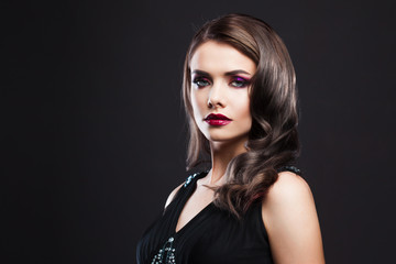 Portrait of a young luxurious woman in a low key. Bright makeup with scarlet lipstick, hairstyle...