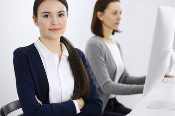 Business woman looking at camera at the background of working colleagues. Office life concept, headshot
