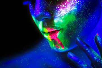 Neonfarbene Lippen und Gesicht, Modemodellfrau im Neonlicht, schöne Modellmädchenlippen mit buntem hellem fluoreszierendem Make-up, Kunstdesign der gemalten Discofrau im UV, buntes Make-up. Nachtclub © Subbotina Anna