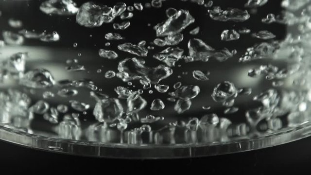 In a kettle with transparent glass walls, water boils. Stainless bottom.