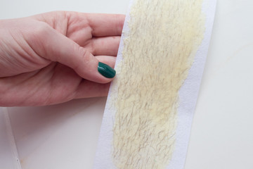  used wax strips on a white background shows a young woman with a beautiful manicure