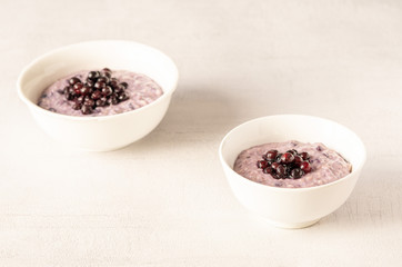 Two oatmeal bowls with blueberries for healthy breakfast isolated on grey background. 