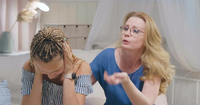 Mature middle aged angry mother scolding teenager informal looking daughter with dreadlocks. Generations conflict, misunderstanding between parents and children in family