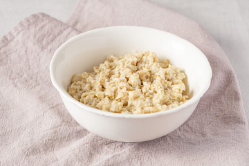 Natural oatmeal bowl on grey napkin. Healthy breakfast. 
