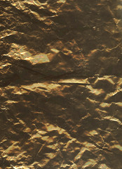 Bronze metallic or plastic imitation of retro foil texture closeup. Crumpled grunge abstract flatlay background. Close-up, vertical, top view, free space. Scratched and dusty, with chips and damages.