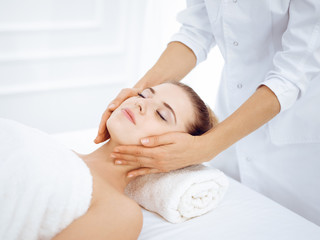 Obraz na płótnie Canvas Young and blonde woman enjoying facial massage in spa salon. Beauty concept